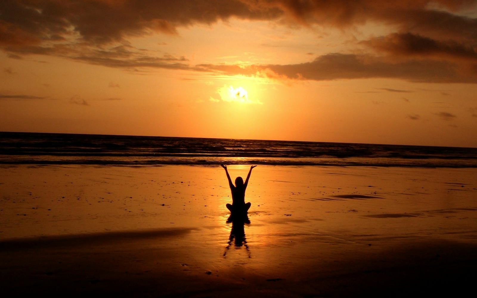 Peaceful meditation silhouette at sunset on a serene beach.